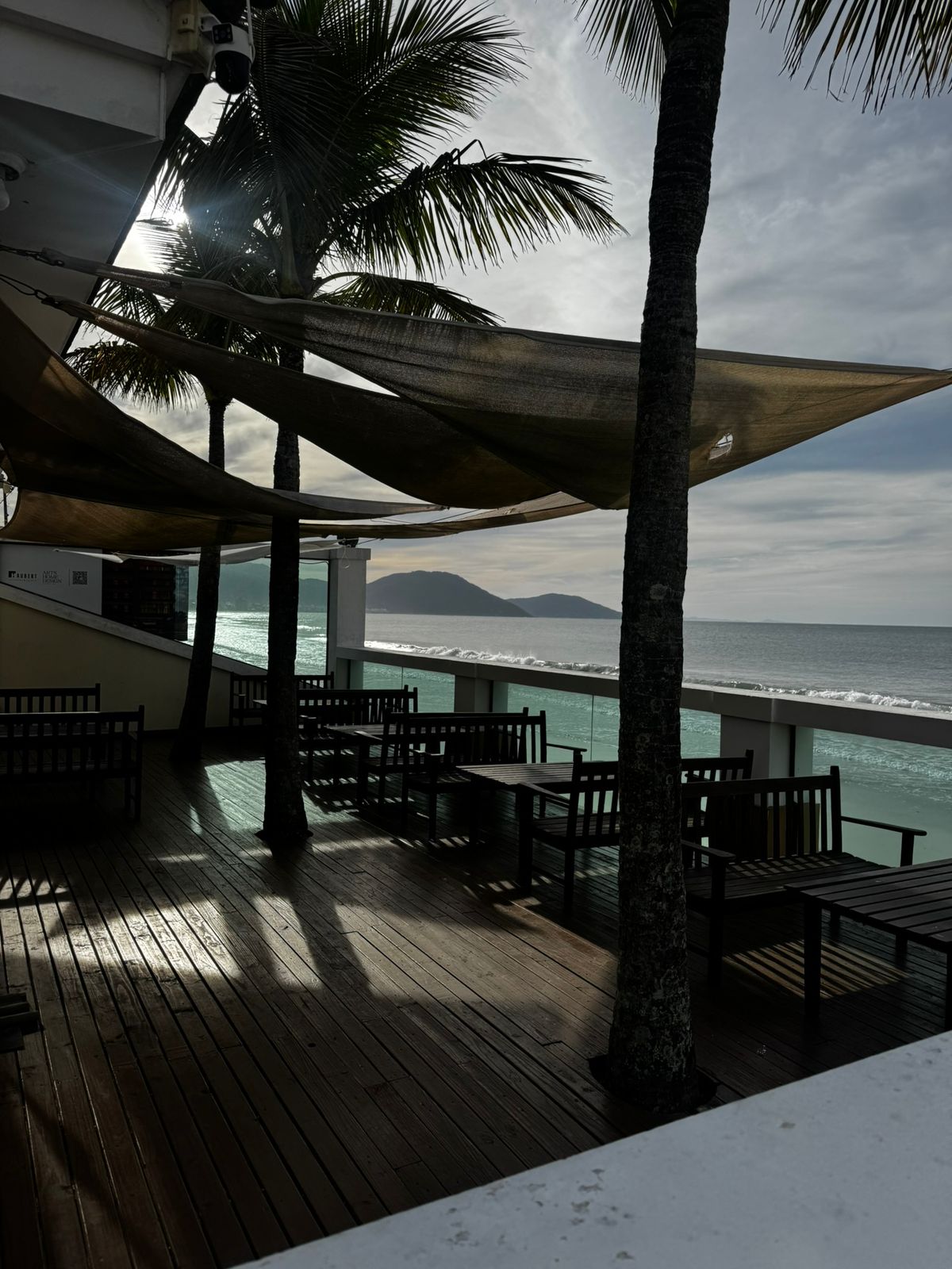 Deck do Portal Beach Club com mesas e vista para o mar